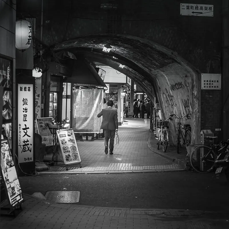 Man walking through a tunnel alley in Tokyo